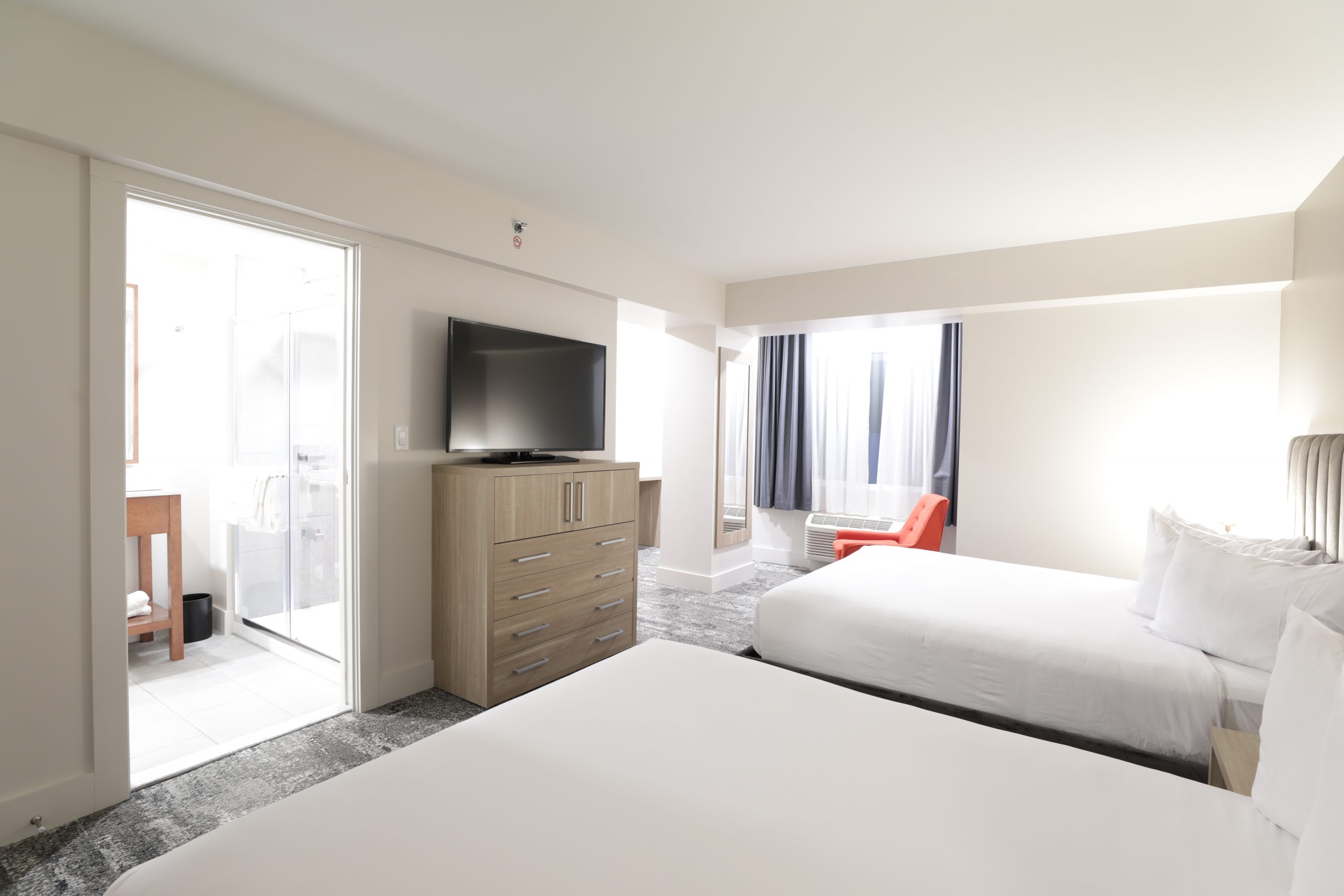 two queen beds, red chair and side view of bathroom