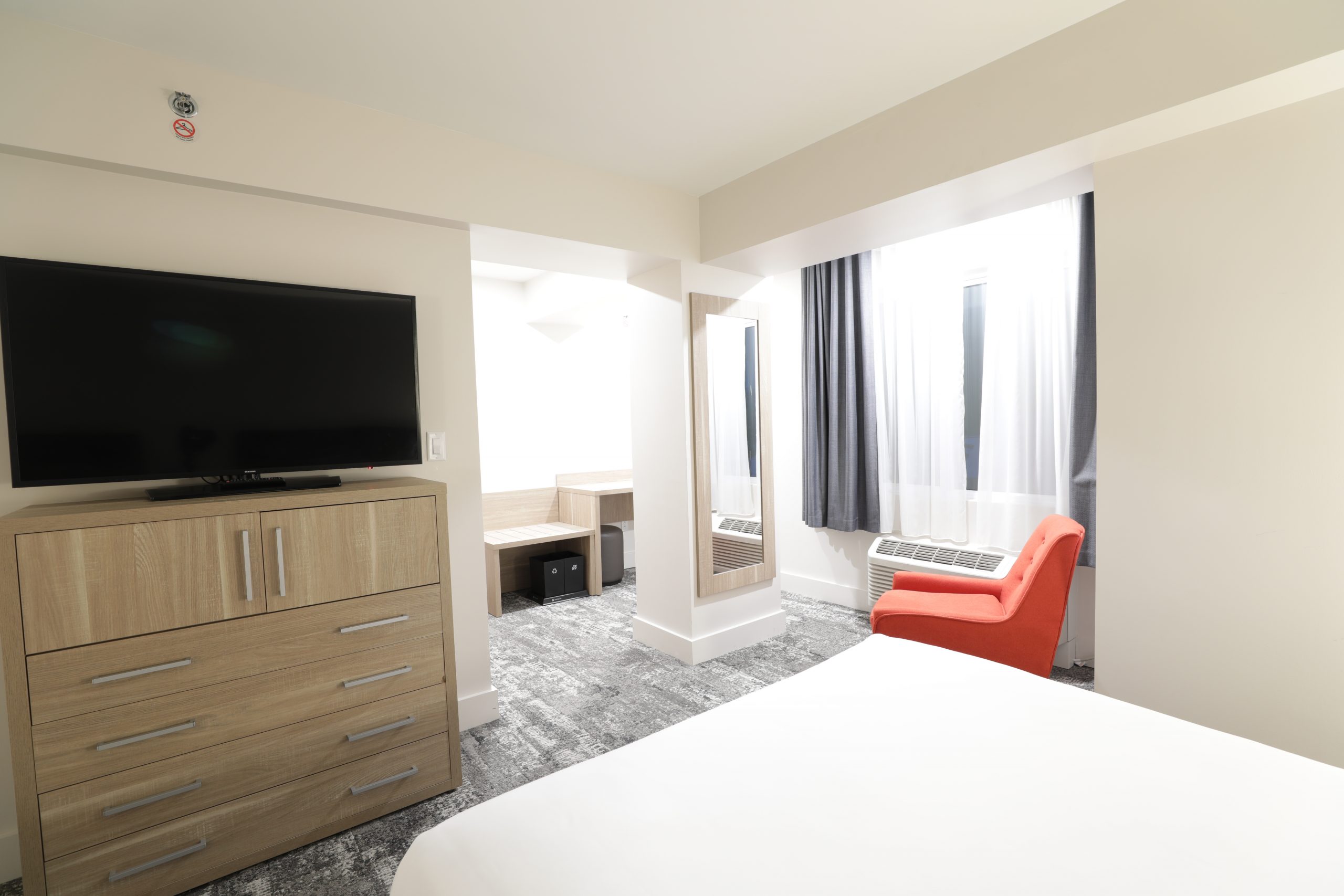 bed with white linen and red chair