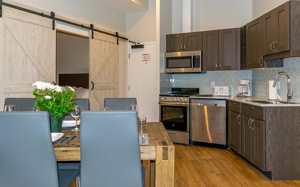 kitchen with 4 person table leading to bedroom behind sliding bar doors