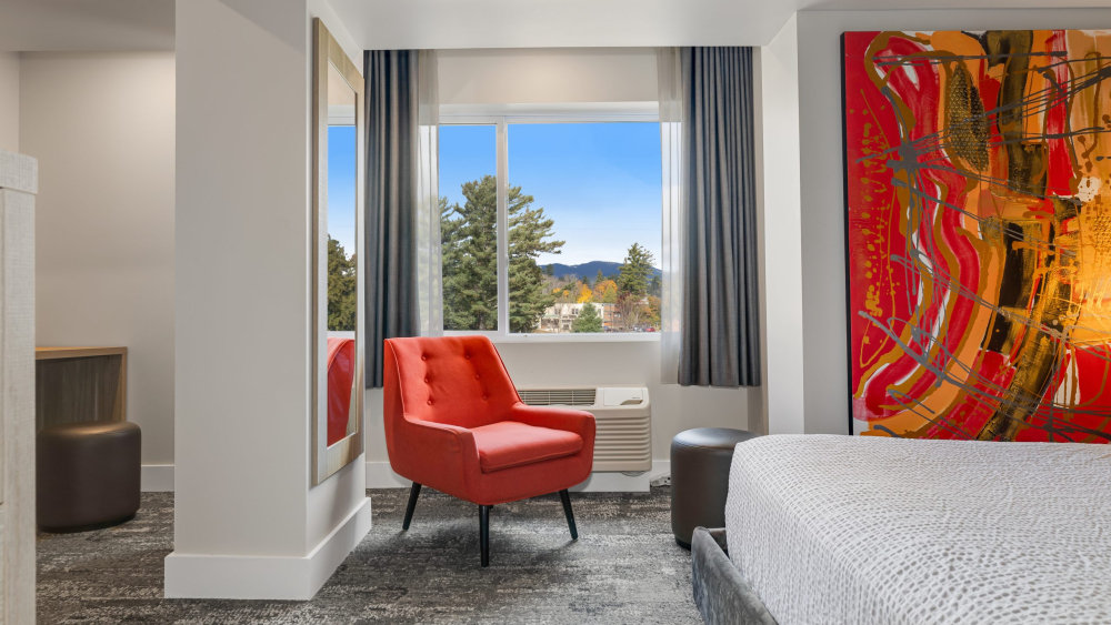 hotel room with large modern art on wall with chair and bed